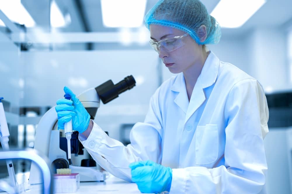 Researcher using a pipette beside test tubes of stain reagents on a laboratory bench for Gram stain preparation